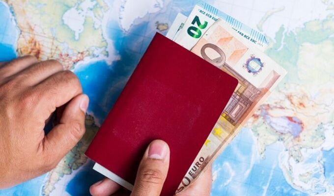 Ilustracja przedstawiająca paszport w którym znajdują się banknoty