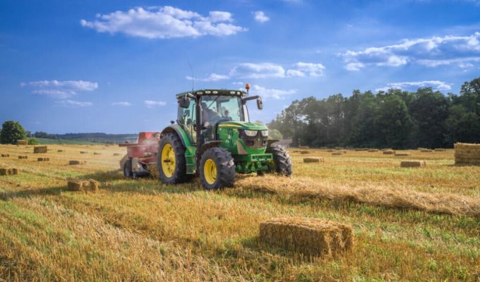 Zdjęcie przedstawiające traktor prasujący słomę